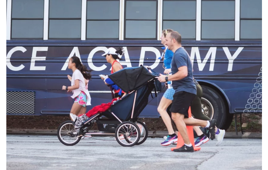 Runners using the Advance Mobility Freedom push chair at a road race