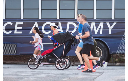 Runners using the Advance Mobility Freedom push chair at a road race