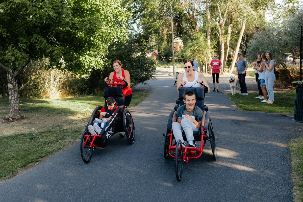 Family enjoying an outdoor path with adaptive mobility chairs